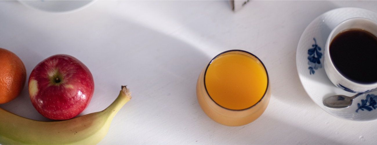 Fruit, a glass of orange juice, and a cup of coffee on a table