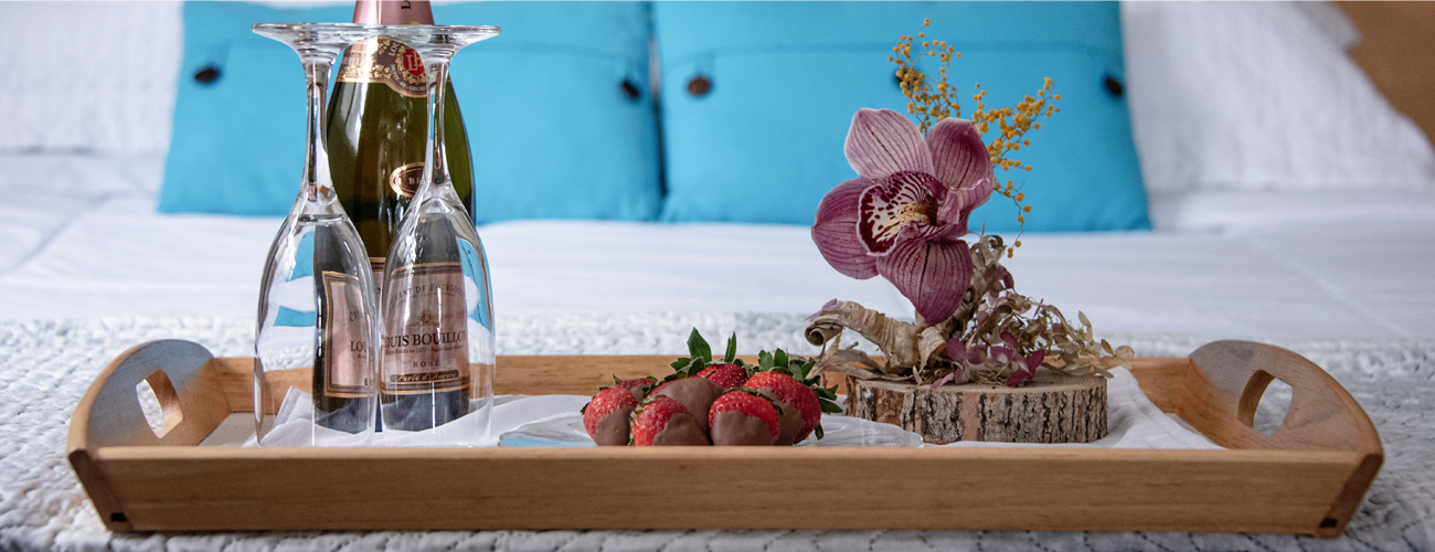 Wood tray with chocolate covered strawberries, wine, and a flower
